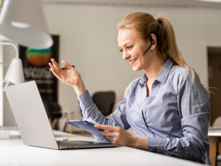 A training adviser at a laptop, taking an enrolment enquiry by headset